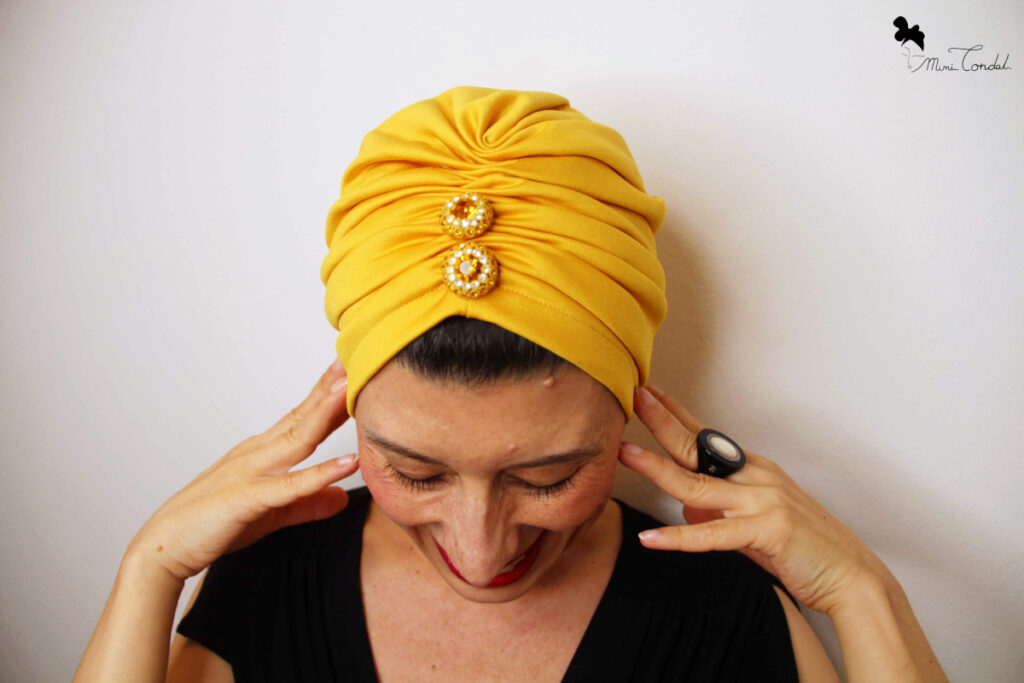 Mimi Condal con turbante giallo decorato con bottoni vintage