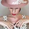 Mimi Condal con cappello canotier rosa con applicazione ricamata bianca.