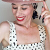 Mimi Condal con cappello canotier rosa con applicazione ricamata bianca.