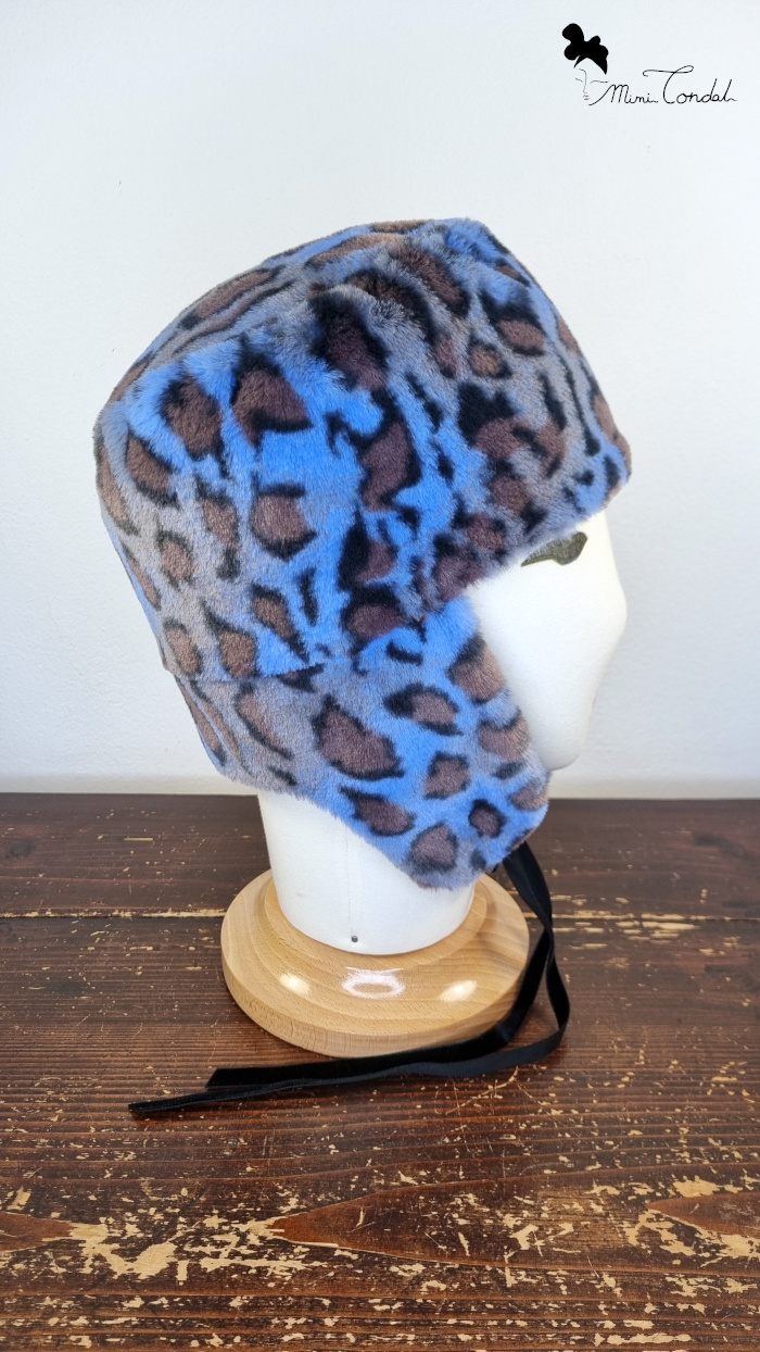 Cappello stile aviatore, con paraorecchie, in pelliccia sintetica leoparda. Mimi Condal.