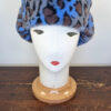 Cappello stile aviatore, con paraorecchie, in pelliccia sintetica leoparda. Mimi Condal.