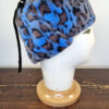 Cappello stile aviatore, con paraorecchie, in pelliccia sintetica leoparda. Mimi Condal.