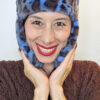 Mimi Condal mostra come indossare cappello stile aviatore, in pelliccia sintetica leoparda, con paraorecchie legate sotto il mento.